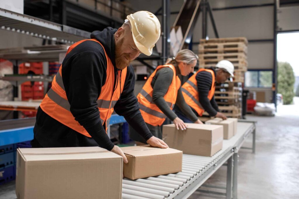 Three warehouse workers on a packing and delivery production line picker packers
